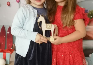 Marysia i Laura pozują do zdjęcia trzymając małego, drewnianego konika.